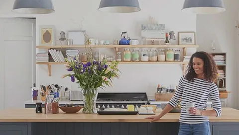 Smilende dame står i moderne kjøkken