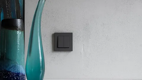 Vase og sort stikk mot grå vegg