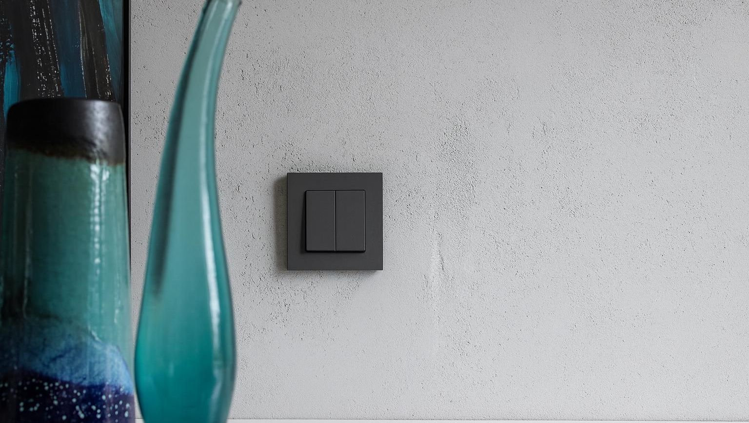 Vase og sort stikk mot grå vegg